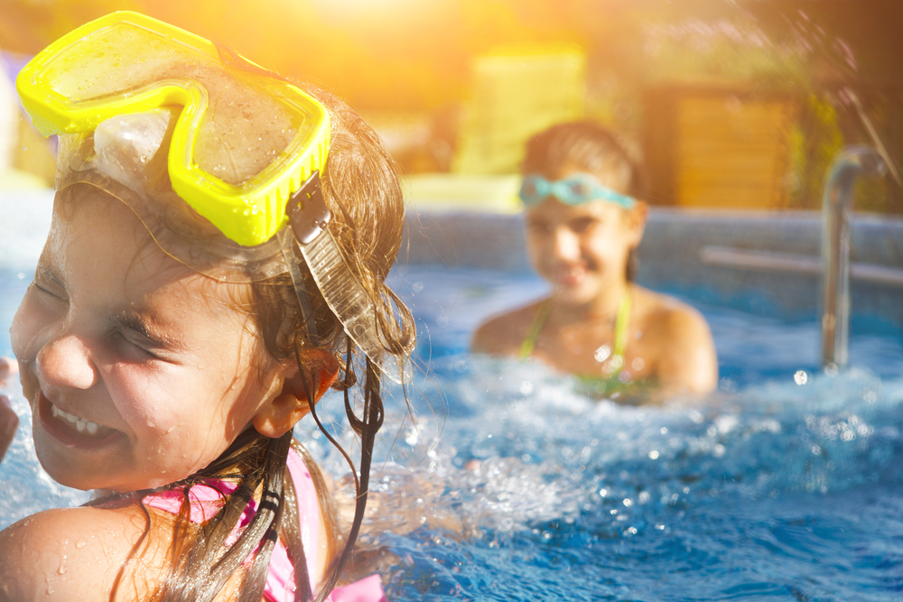 Barn som leker i poolen. Två små flickor har kul i poolen. Sommarlov och semesterkoncept